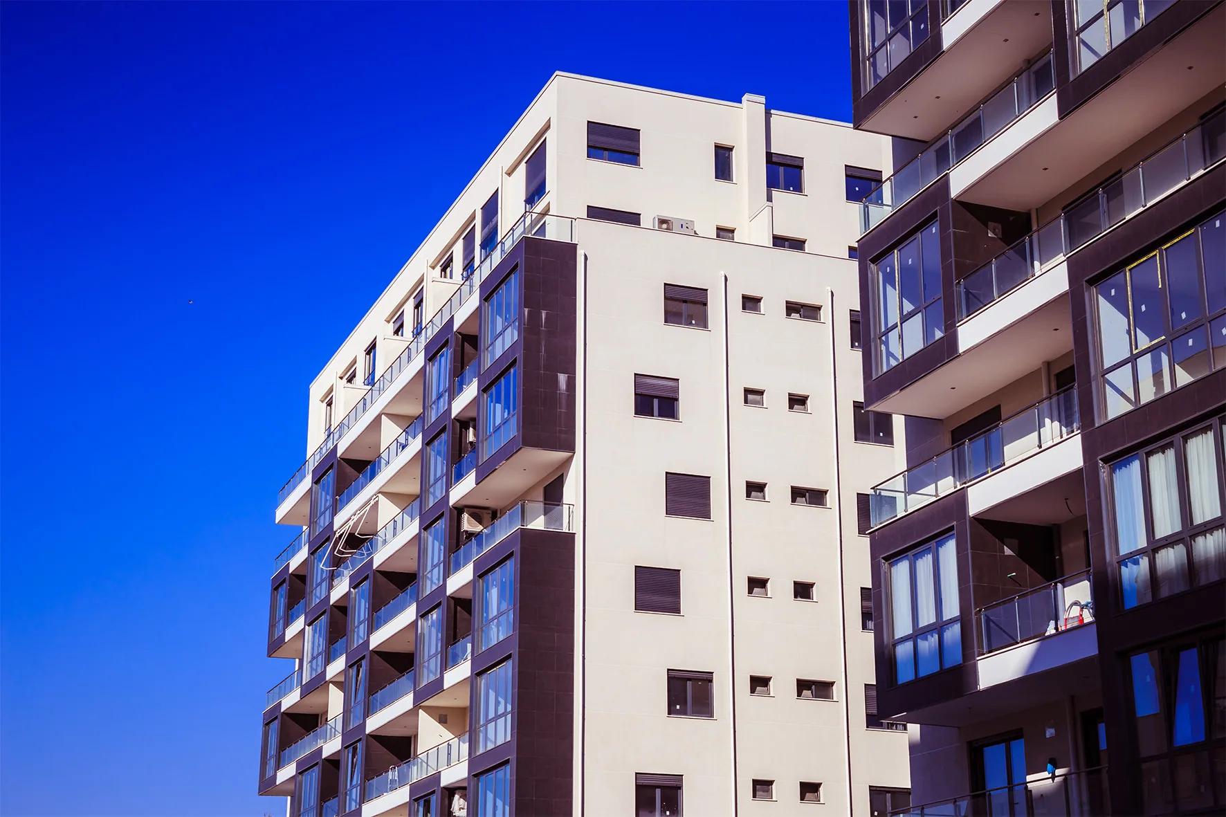 Corner elevation in white render with recessed balconies