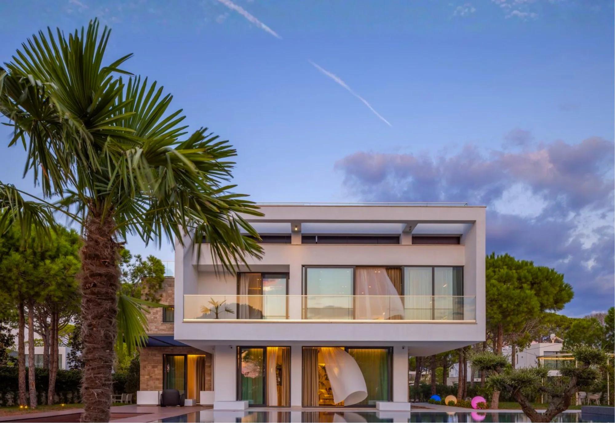 A villa framed by a palm tree at dusk