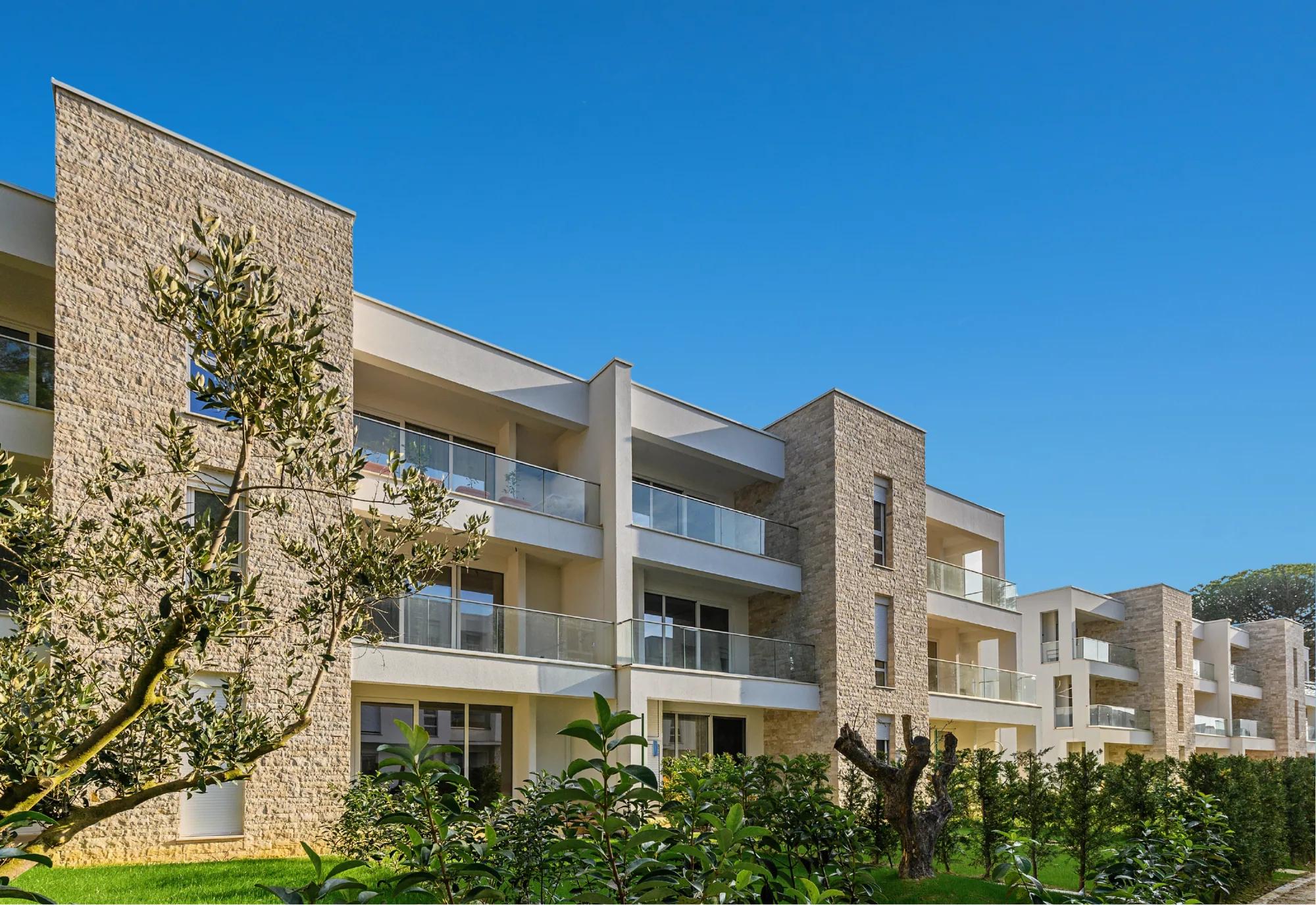 Stone-clad apartment elevation with olive trees in the foreground